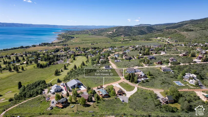 Aerial landscape featuring a vibrant lake, rolling hills, and a golf course