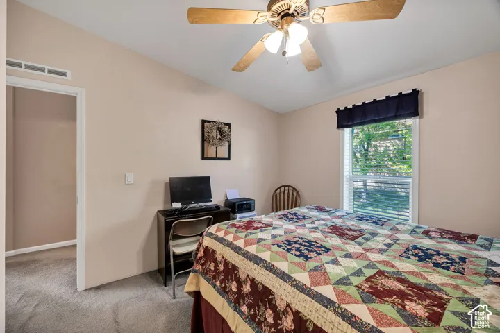 Carpeted room featuring an angled ceiling, a ceiling fan with light fixture, and a window with blinds