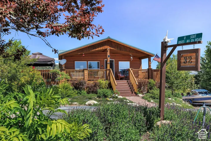 Log-sided residence with a covered porch, wood deck, and an extensive surrounding landscape