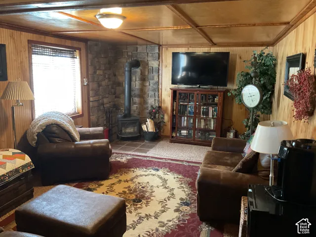 Living area featuring wood-finish paneling, a stone-clad corner, and a freestanding wood-burning stove