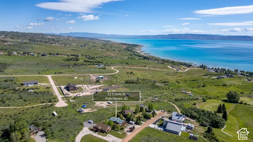 Expansive aerial overview showcasing a residential area with a prominent body of water, distant mountains, and varied terrain