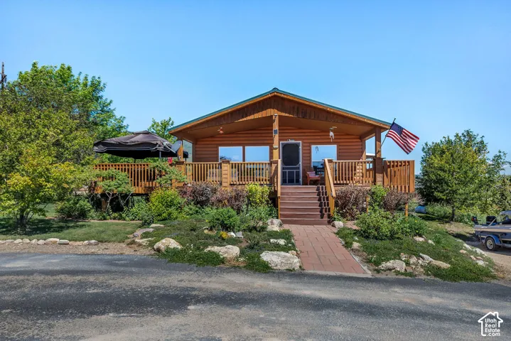 Wood-sided home with a covered front porch, an expansive wooden deck, and a red brick pathway