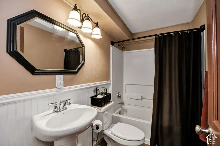 Bathroom featuring a white pedestal sink with chrome faucet, a wall-mounted octagonal mirror, and a three-light vanity fixture