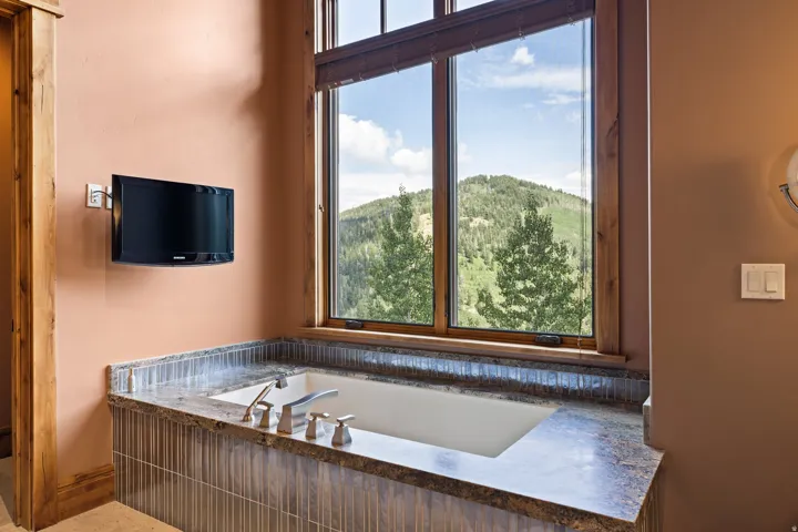 Built-in soaking tub with a stone countertop and tile surround