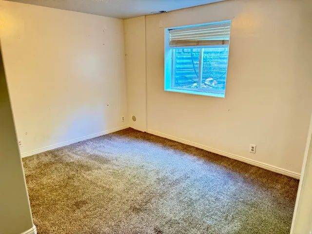 Carpeted room featuring a single window with horizontal blinds, white baseboards, and neutral wall tones