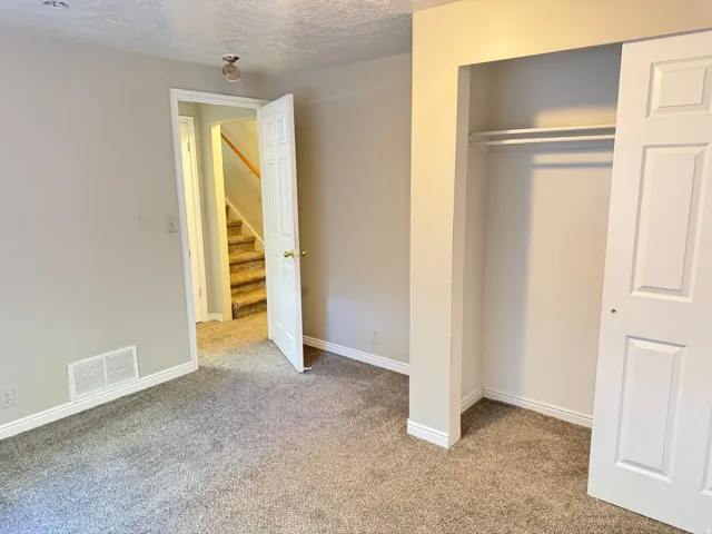 Carpeted interior space with a built-in closet featuring bi-fold doors and shelving