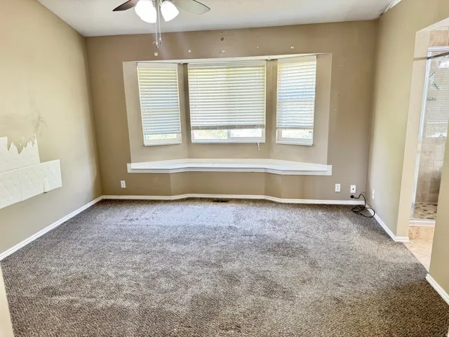 Spacious room featuring a bay window with a built-in bench, ceiling fan with integrated lighting, and carpet flooring