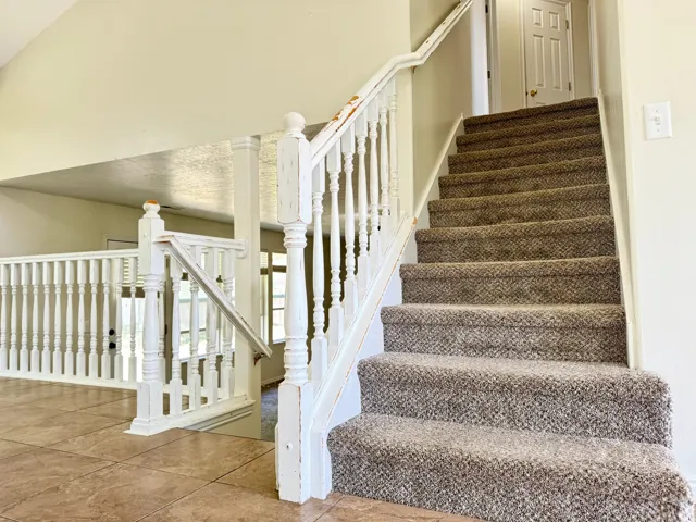 Carpeted staircase featuring white painted banisters and balusters