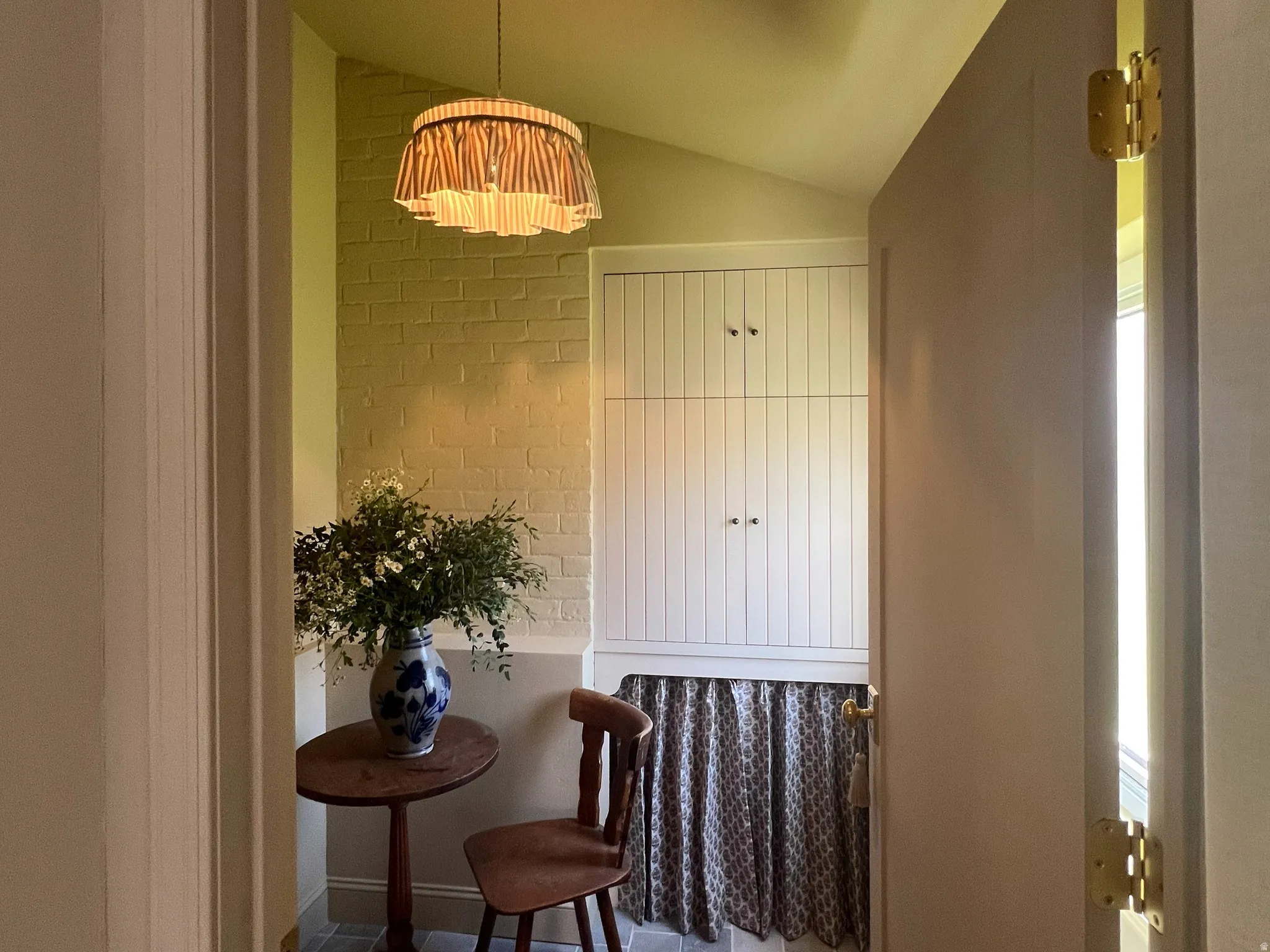 Entryway featuring a decorative pendant light, brick accent wall, built-in cabinetry, and patterned floor tiling