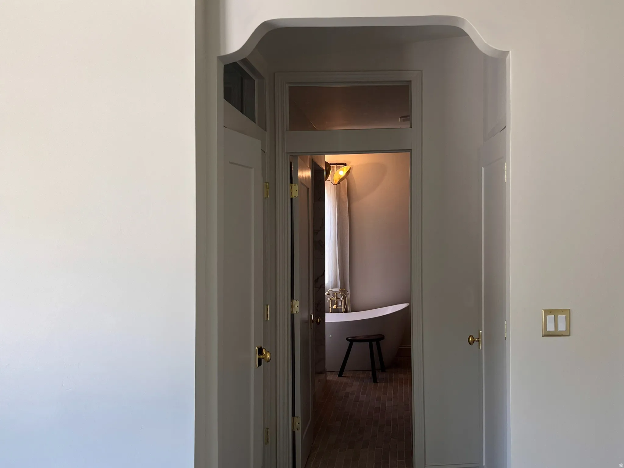 Arched doorway leading to a bathroom featuring a freestanding soaking tub and patterned tile flooring