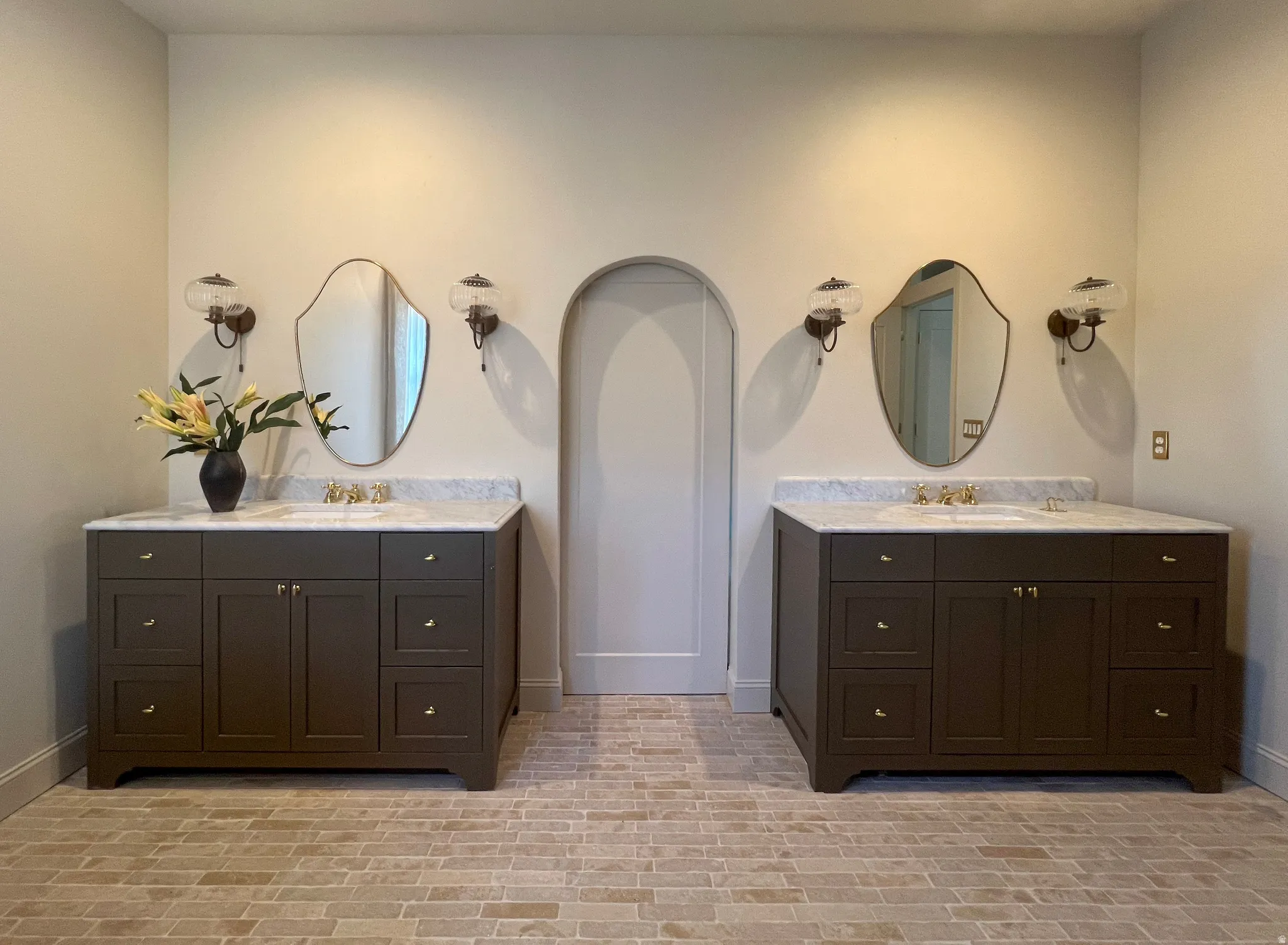Dual vanities with white stone countertops, integrated sinks, and brass-finish fixtures