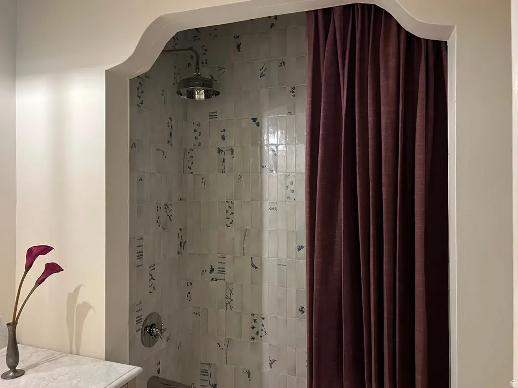 Alcove shower featuring decorative tiled walls, a rain showerhead, and a chrome mixing valve