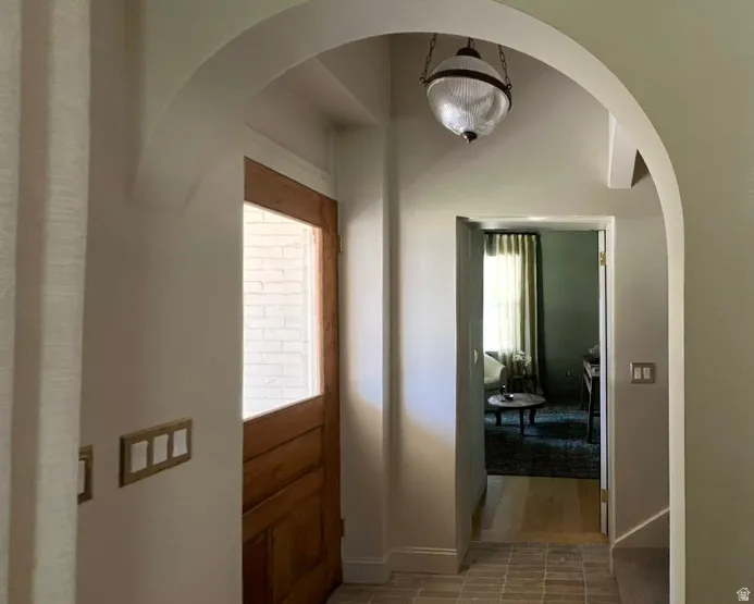 Entryway featuring a wood-panel door with glass inserts, arched doorways, a globe pendant light, and tiled flooring