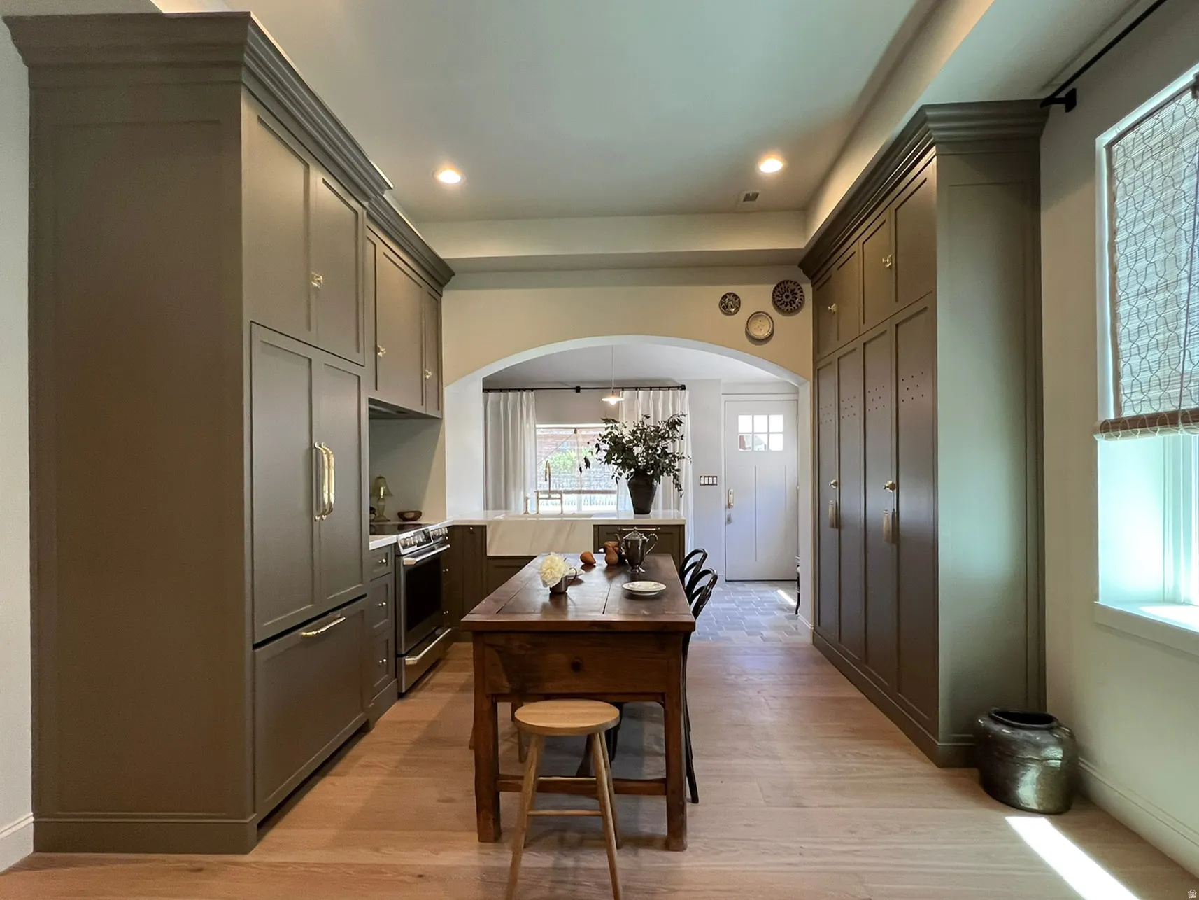 Expansive kitchen featuring custom floor-to-ceiling cabinetry, integrated refrigerator, professional-grade range, and wood-finish flooring