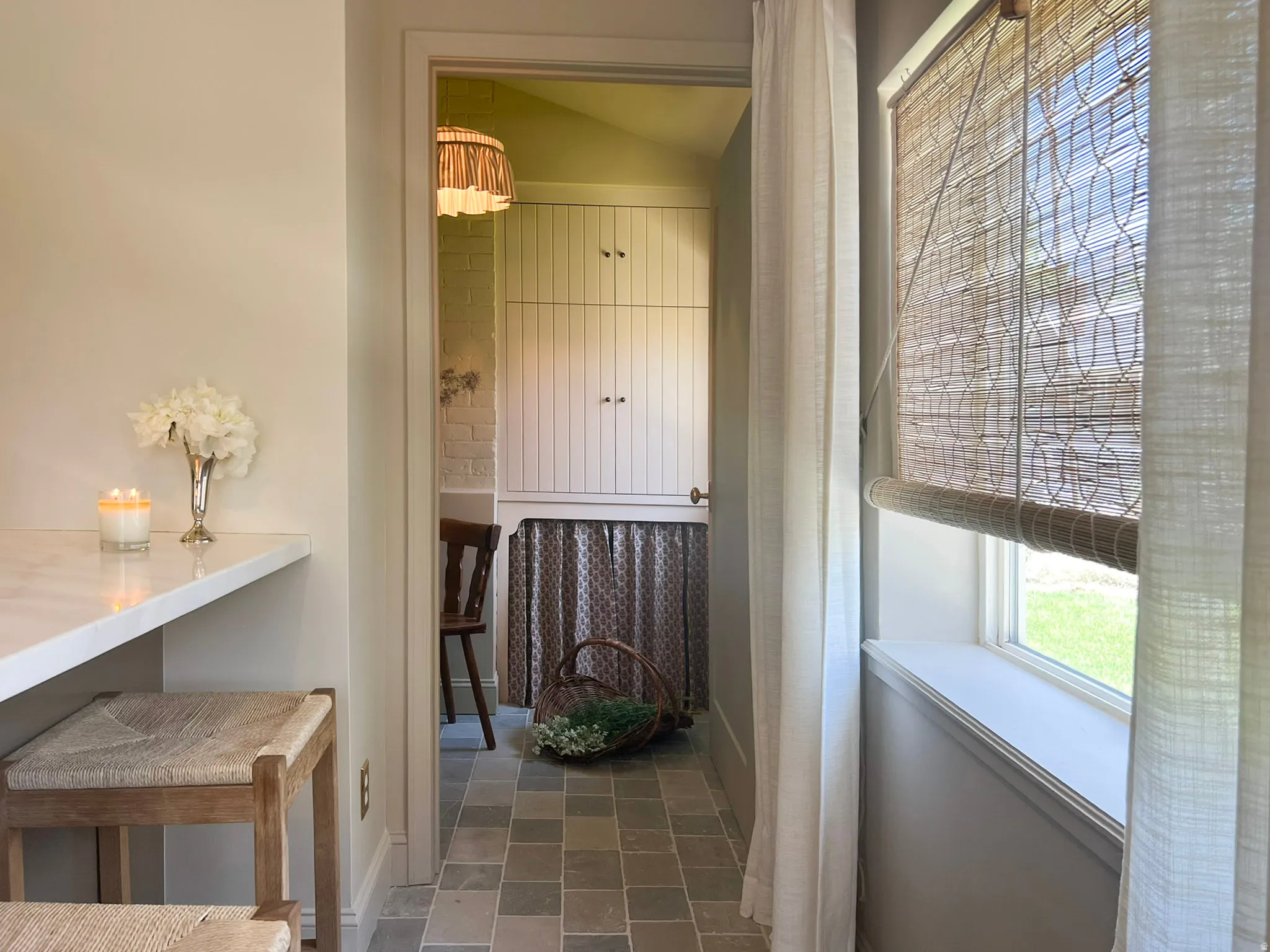 Open doorway revealing a utility area with built-in cabinetry, a geometric pendant light fixture, and square tile flooring