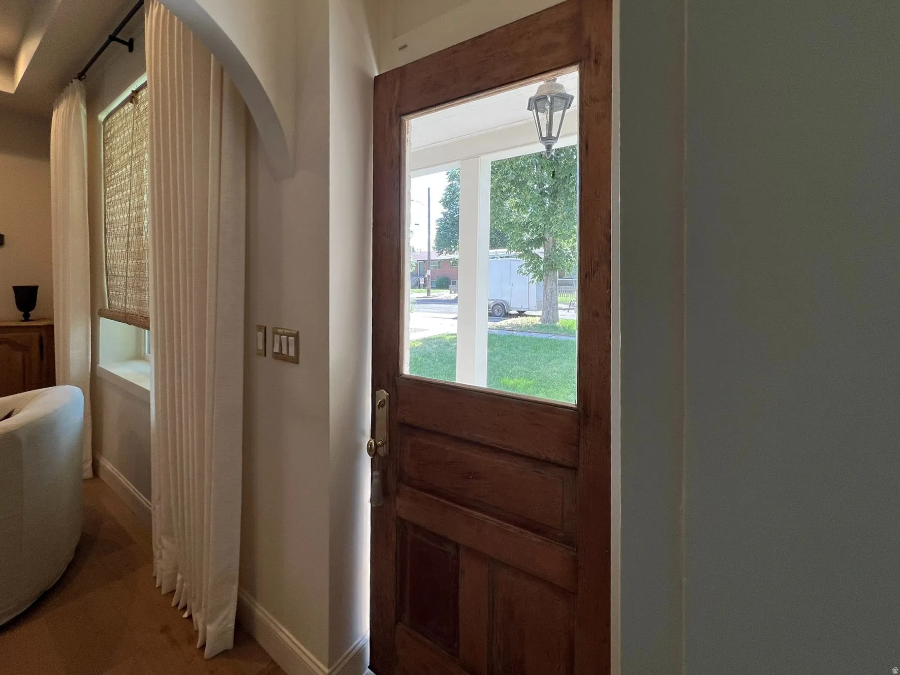 Solid wood entry door with glass paneling, brass hardware, and a classic porch light fixture