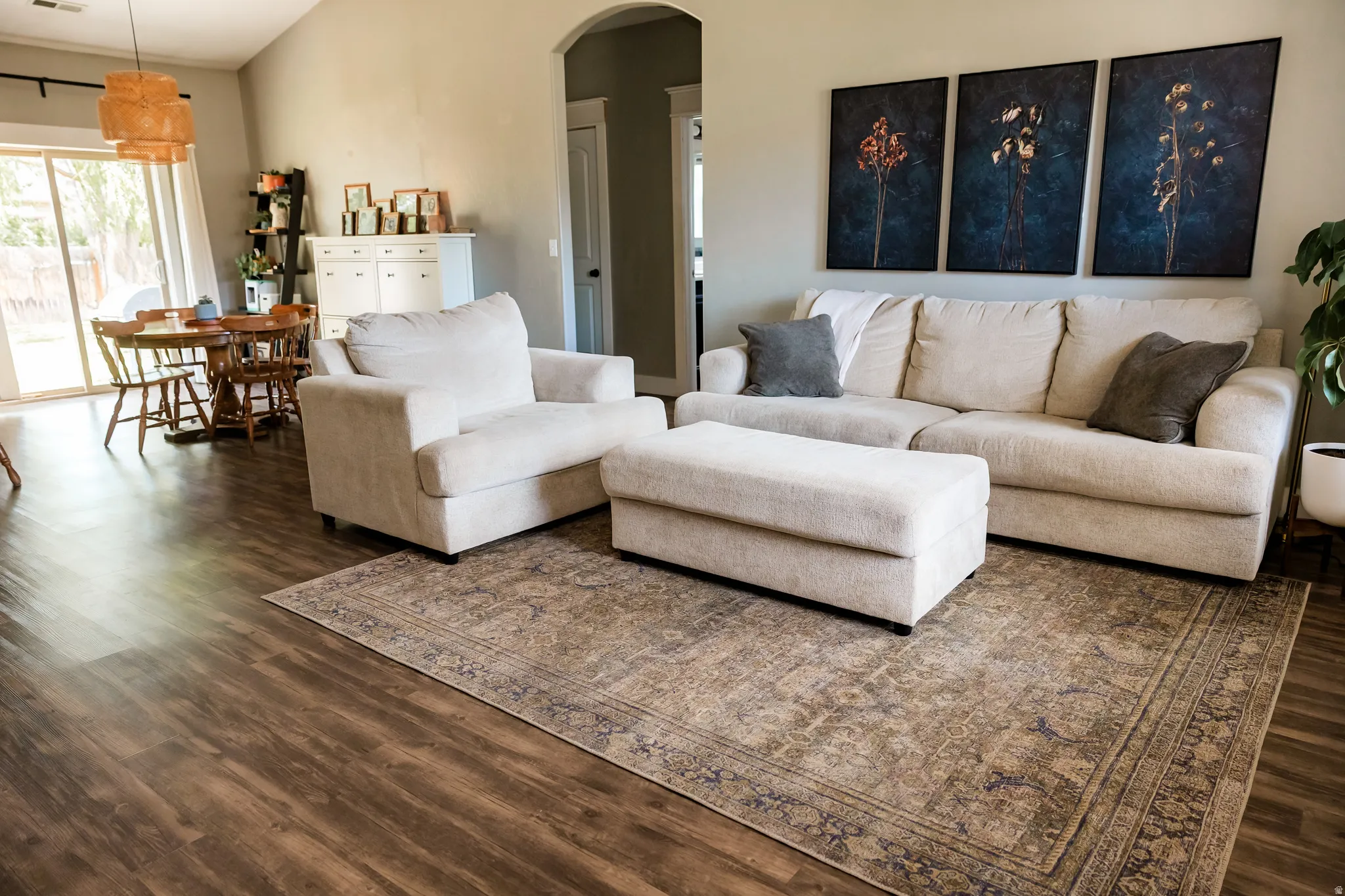 Spacious living area featuring wood-finish flooring, a vaulted ceiling, and an arched doorway