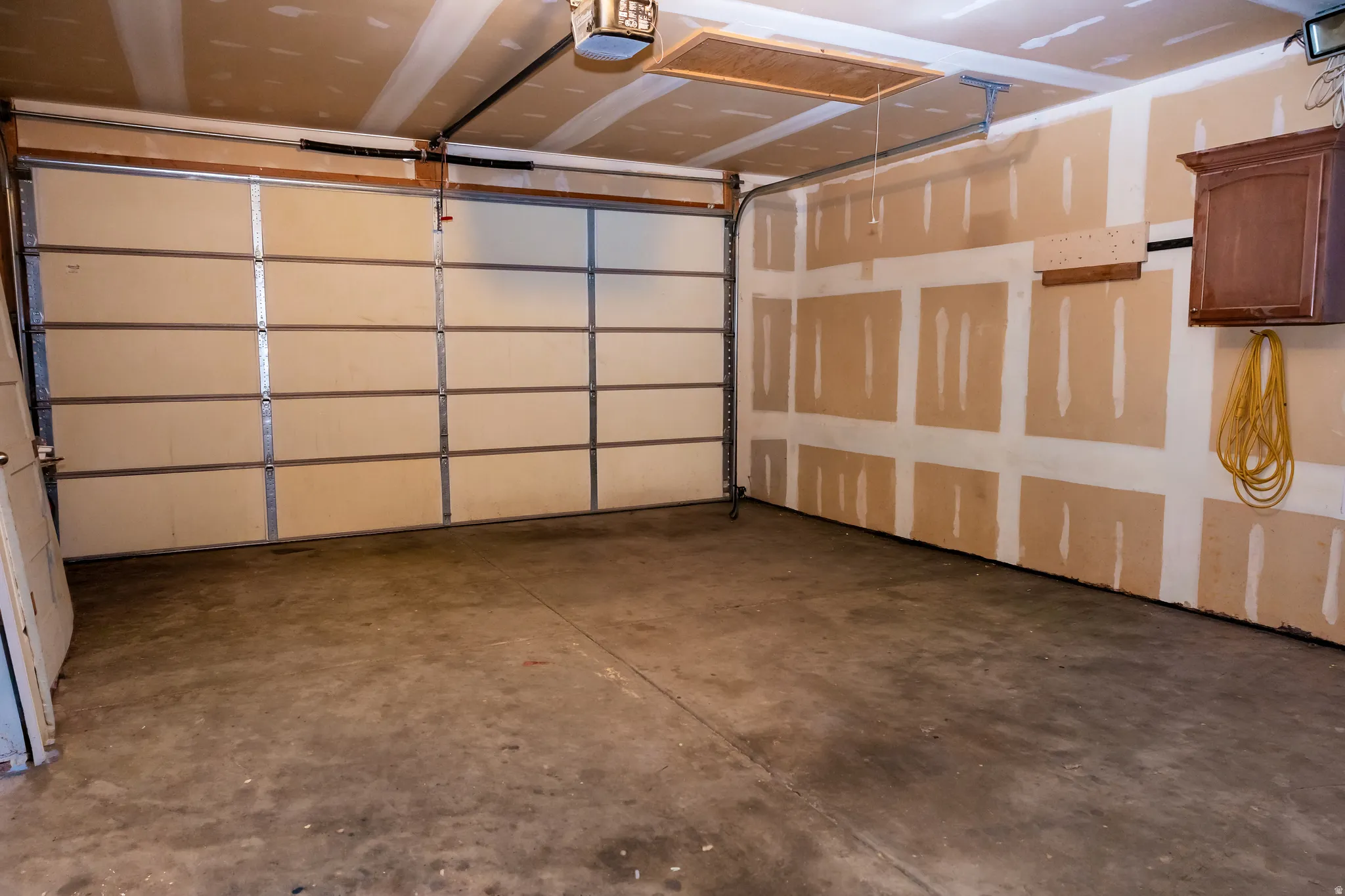 Spacious garage featuring a concrete floor, overhead lighting, and an automatic garage door opener
