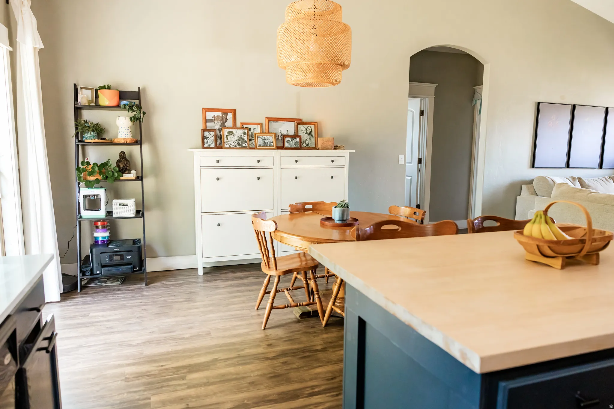 Open concept interior featuring wood-finish flooring, a kitchen island with a light-toned countertop, and an arched doorway
