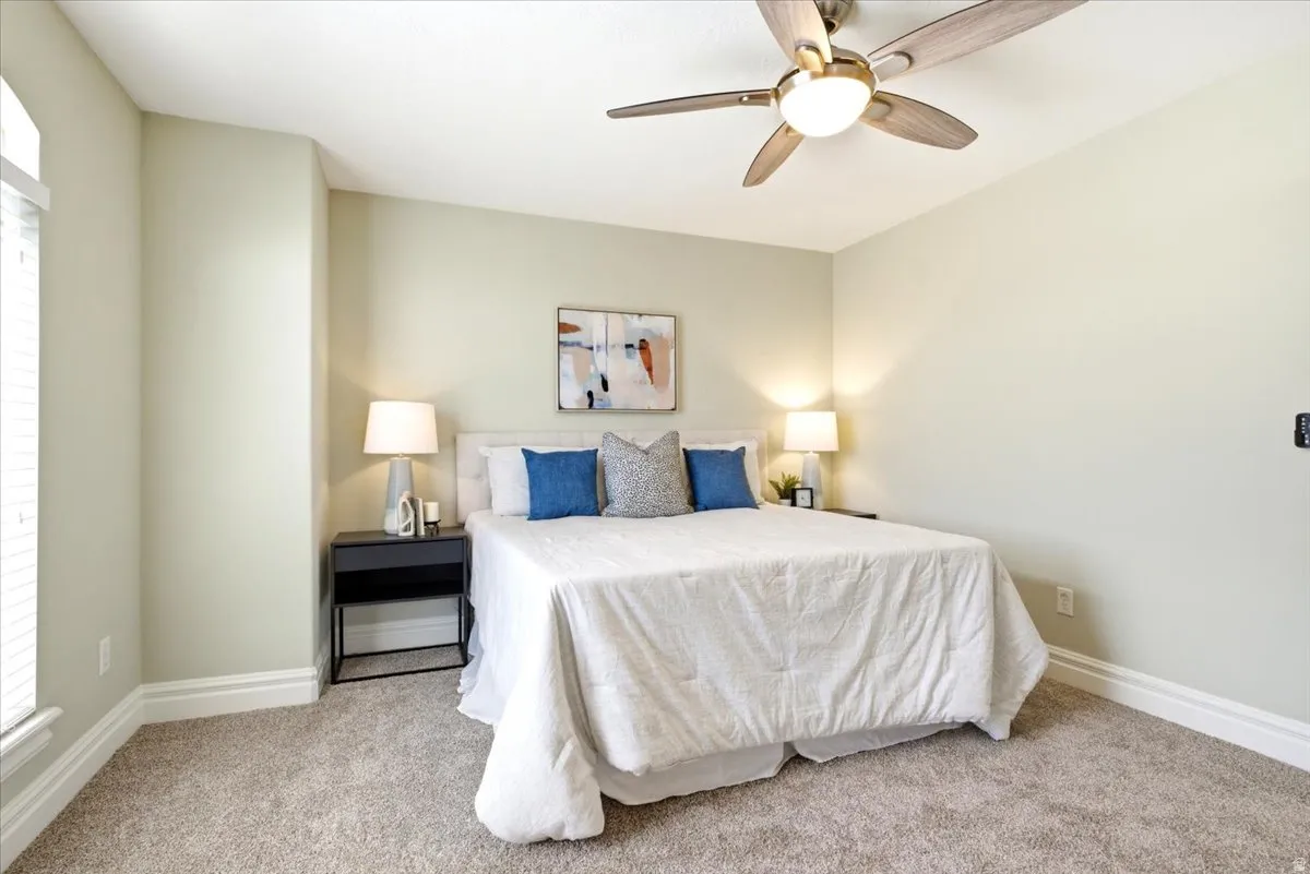 Bedroom featuring a ceiling fan with light fixture, neutral wall paint, and plush carpet flooring