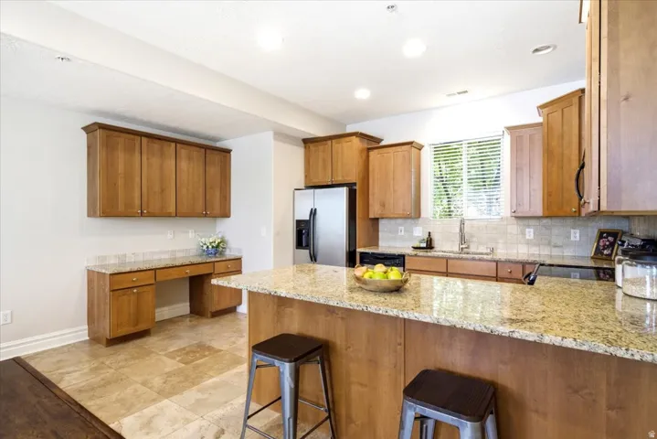 Kitchen featuring light wood cabinetry, stone-finish countertops, stainless steel appliances, and tile flooring