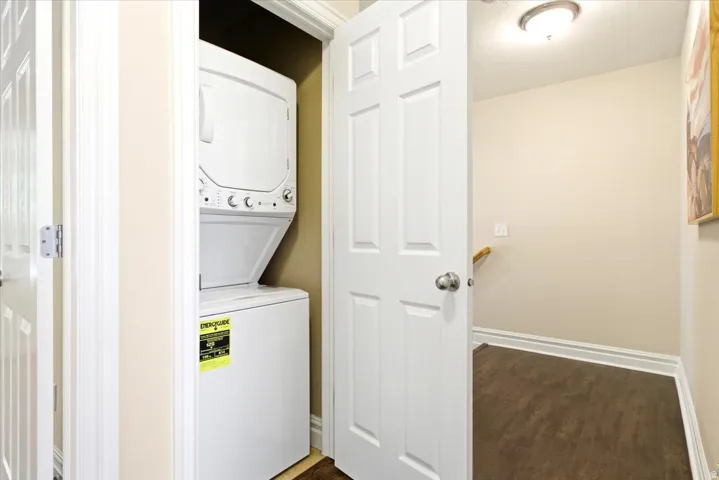 Dedicated laundry closet featuring a white stacked washer and dryer unit