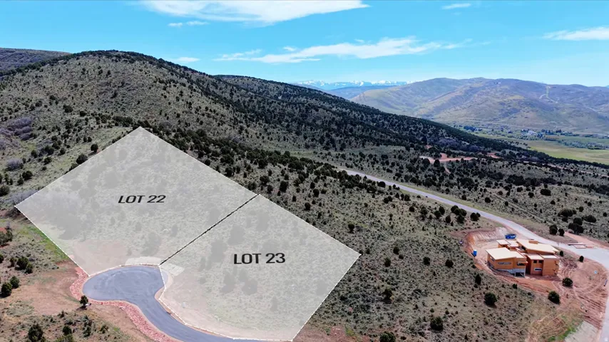 Mountainous terrain featuring two highlighted building lots (Lot 22 and Lot 23) situated along a paved road