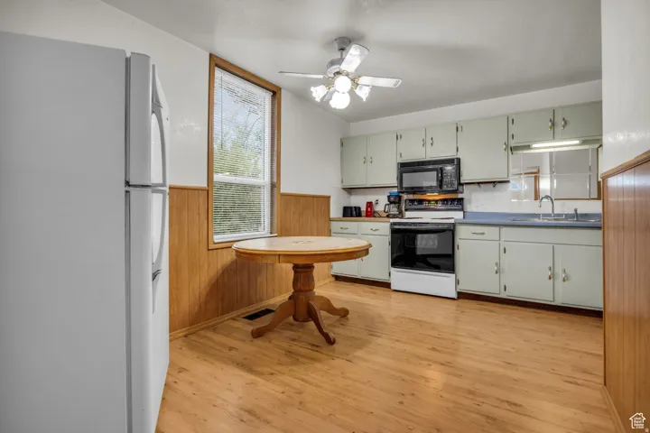 Kitchen featuring light wood-finish flooring, light green cabinetry, a built-in microwave, and a ceiling fan with light fixture