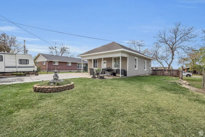 Expansive front yard featuring a manicured lawn, a decorative fountain within a brick-bordered bed, a covered front porch, and horizontal siding