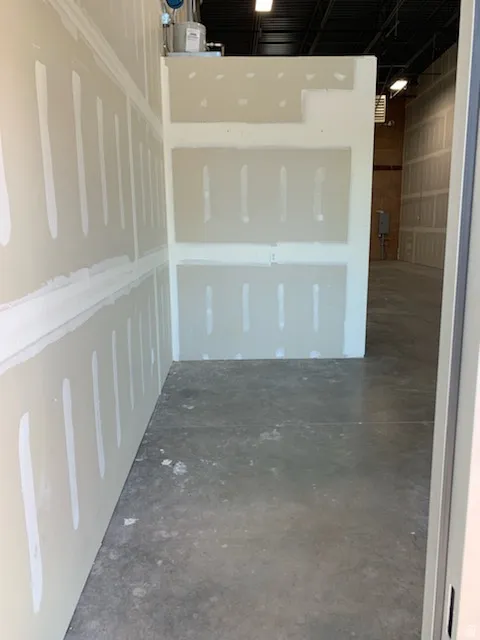 Unfinished interior space featuring drywall installation, exposed concrete flooring, and an open ceiling with visible ductwork