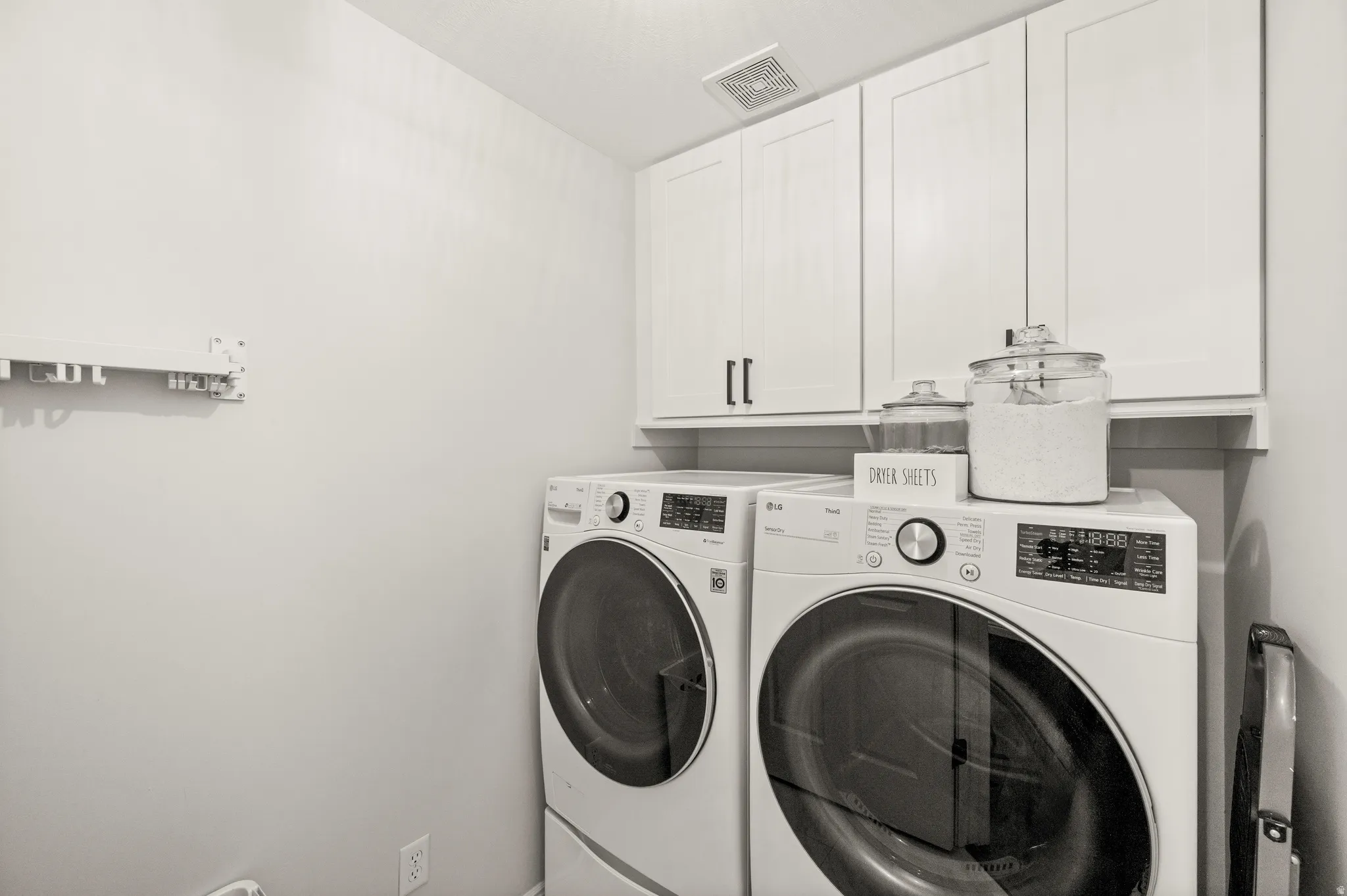 Laundry area featuring white cabinetry with dark hardware and a built-in shelf