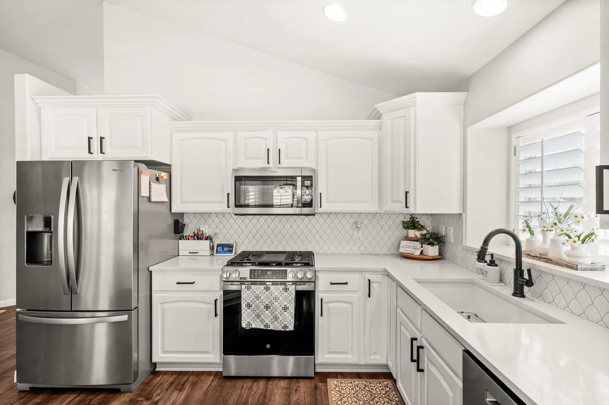 Modern kitchen with white cabinetry, stainless steel appliances, and wood-finish flooring