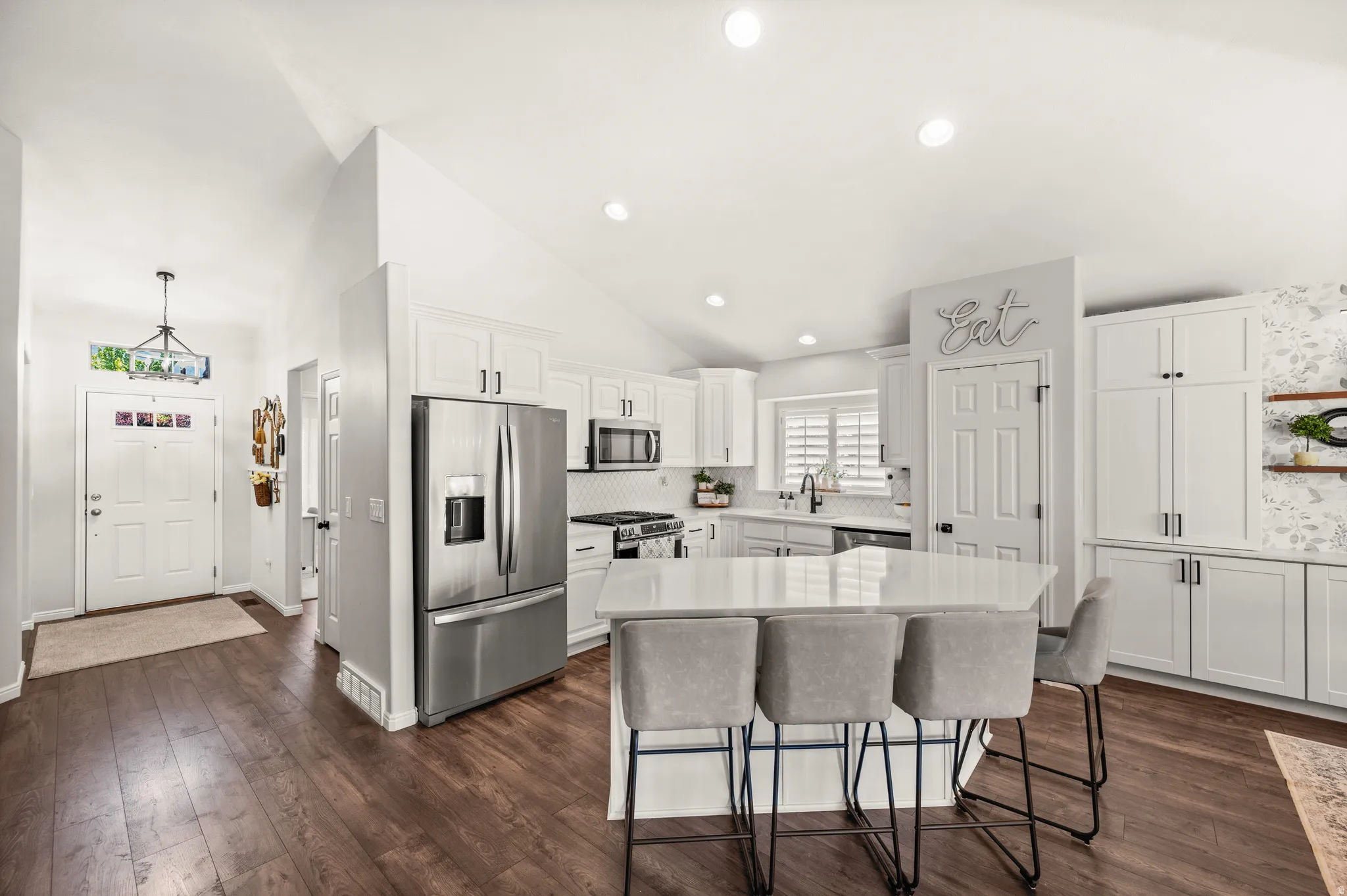 Modern kitchen featuring white cabinetry, stainless steel appliances, a center island with countertop seating, and wood-finish flooring