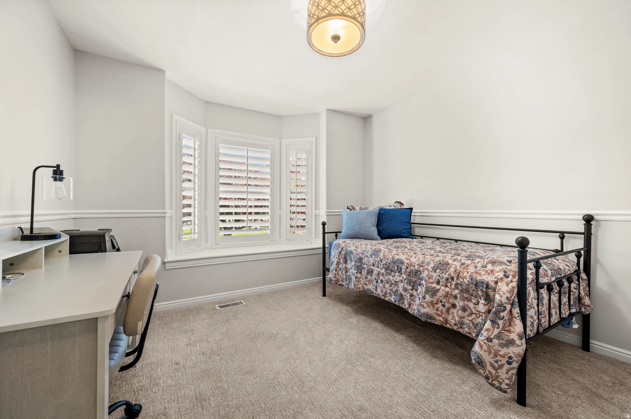 Bay window with plantation shutters, neutral wall tones, white chair rail molding, textured carpet flooring, and a semi-flush mount ceiling light fixture