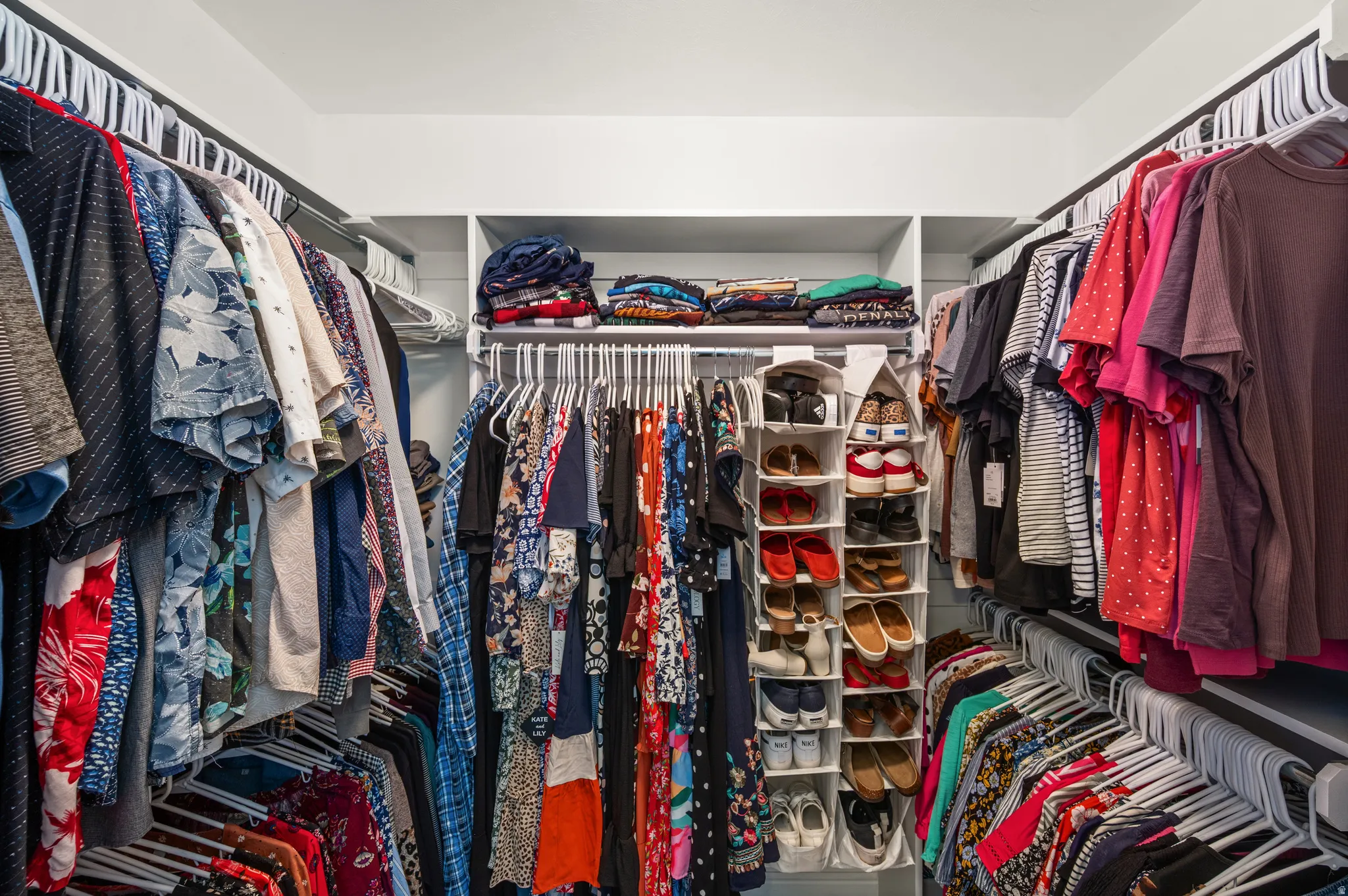 Walk-in closet featuring extensive built-in shelving, multiple hanging rods, and ample storage capacity