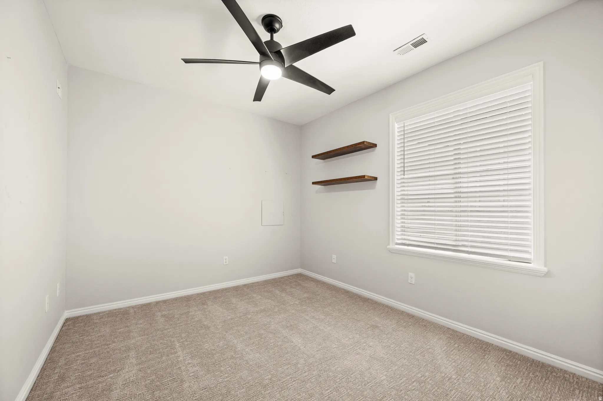 Neutral-toned carpeting extends throughout this room, featuring a modern ceiling fan with integrated lighting