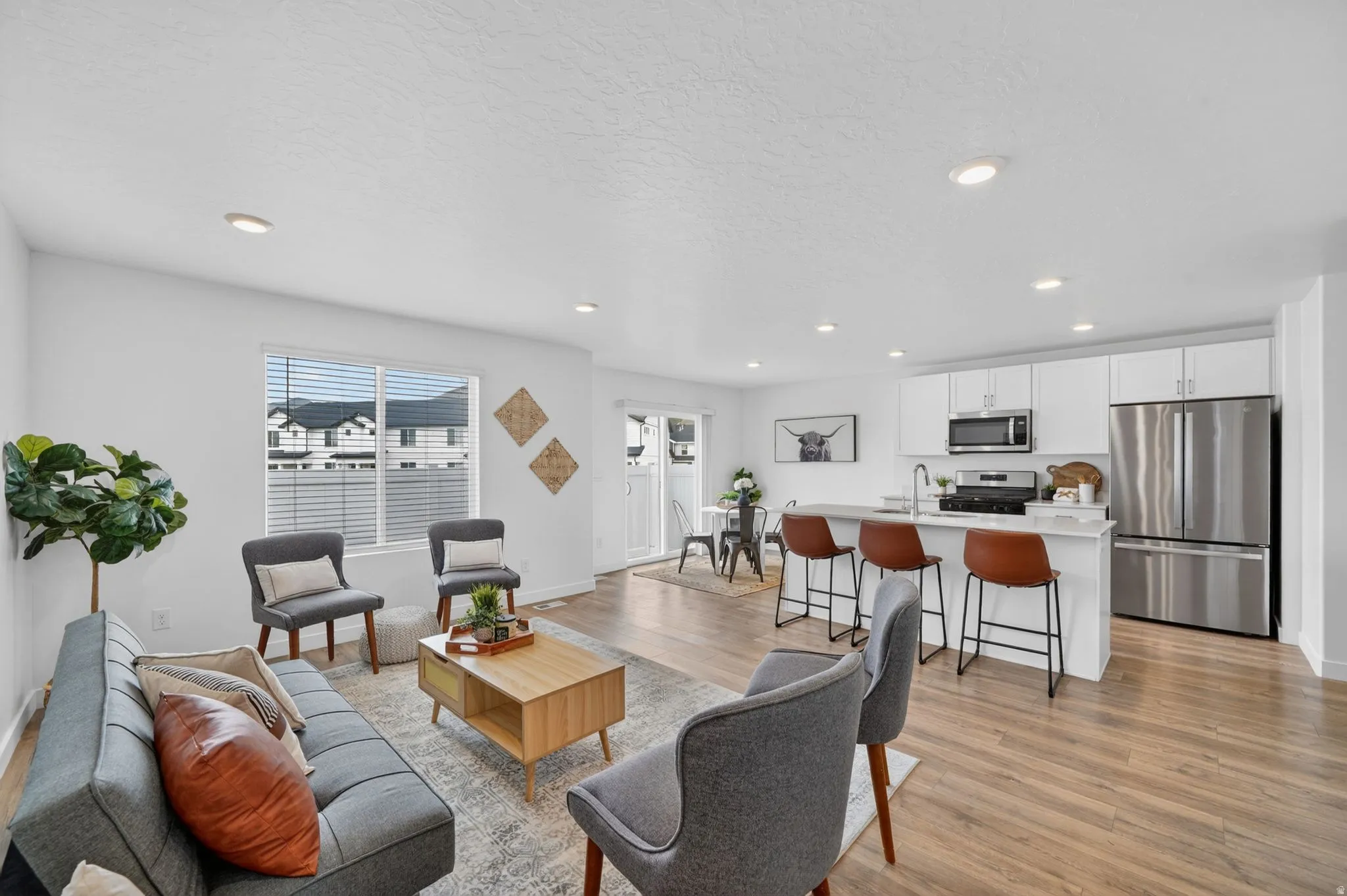 Open-concept living space featuring wood-finish flooring, recessed lighting, and a kitchen with white cabinetry