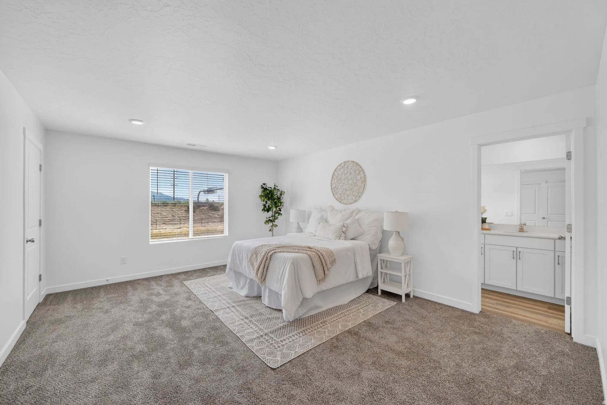 Spacious interior room featuring plush carpet flooring, recessed lighting, and a wide window with mountain scenery