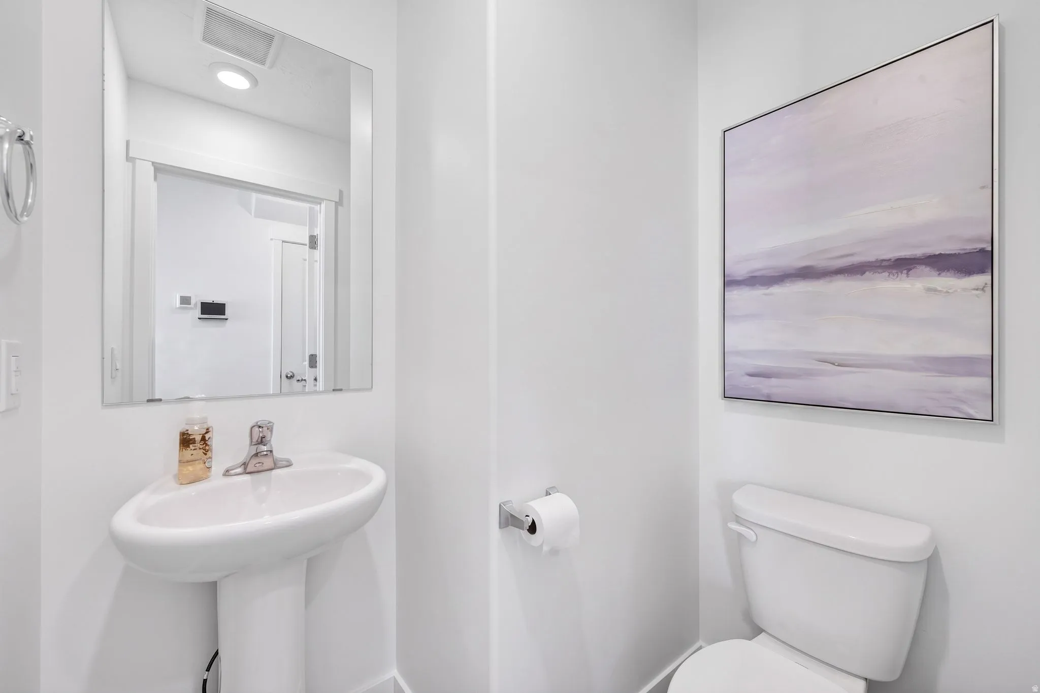 Pedestal sink with chrome fixtures, framed mirror, and recessed lighting