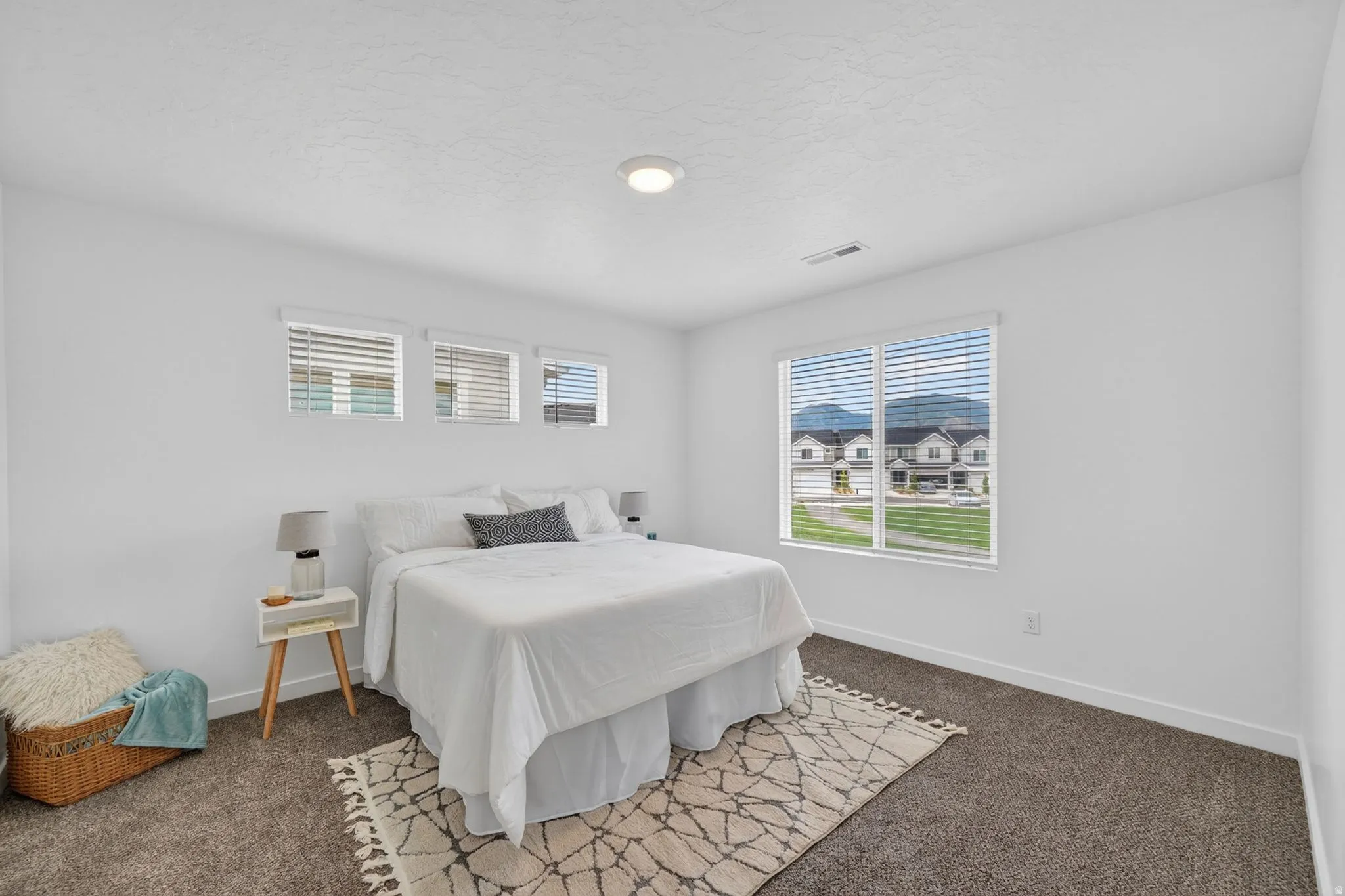 Carpeted room featuring a large window, three smaller windows, and a flush-mount ceiling light