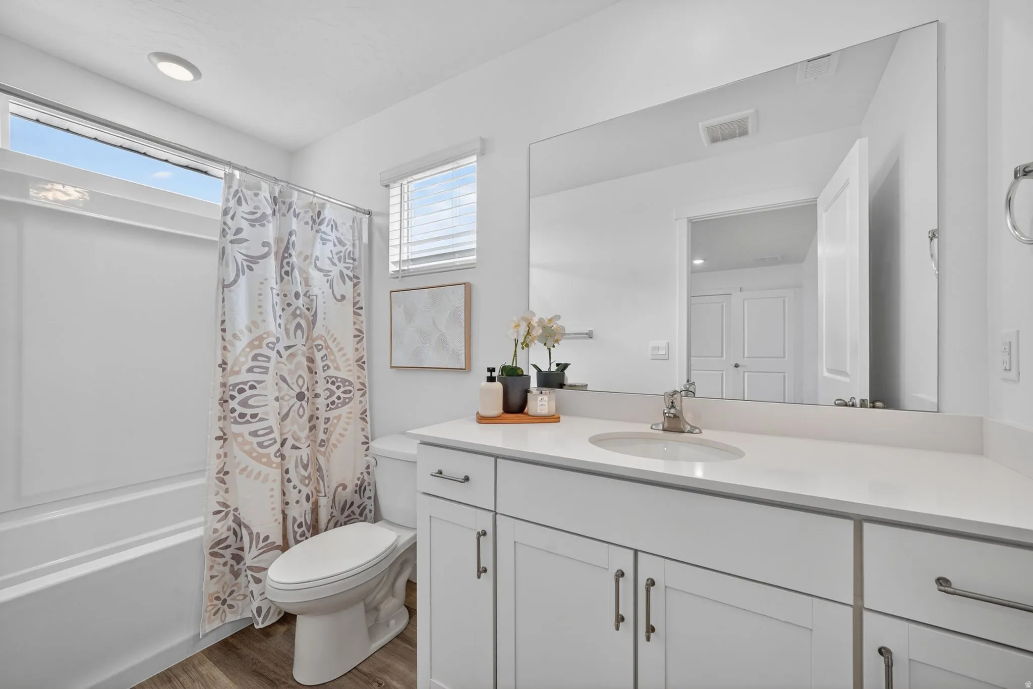 Bathroom featuring a white vanity with an integrated sink, polished chrome faucet, and expansive mirror
