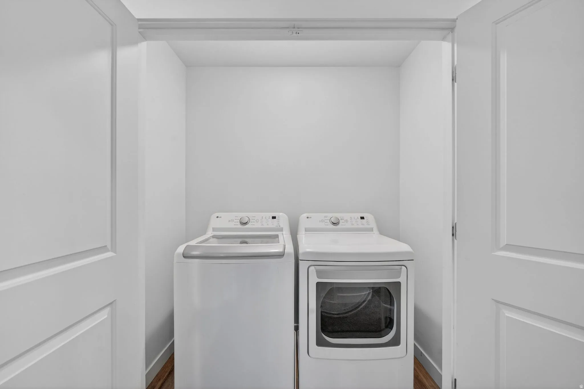 Dedicated laundry closet featuring wood-finish flooring
