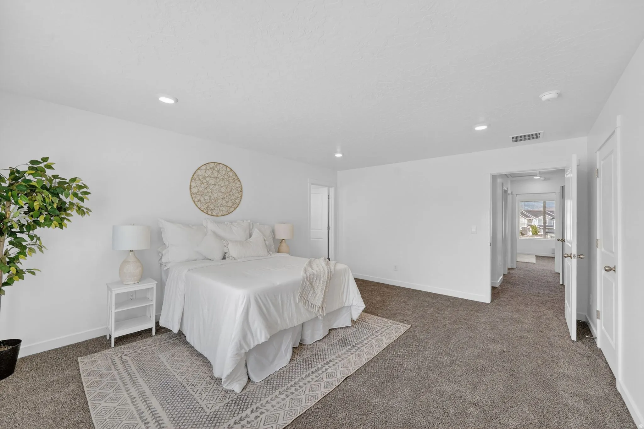 Spacious bedroom featuring neutral carpeting, recessed ceiling lighting, crisp white walls, and white trim