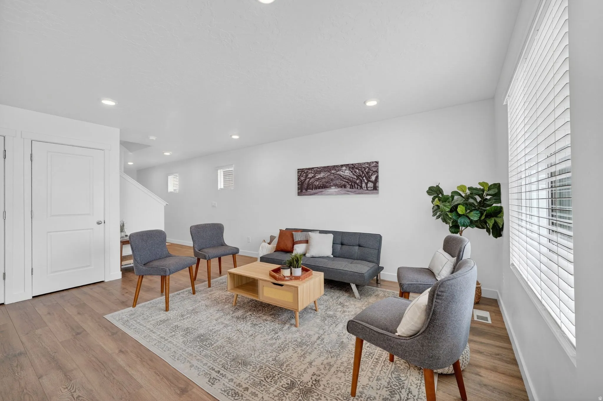 Spacious room featuring wood-finish flooring, white walls, and recessed lighting