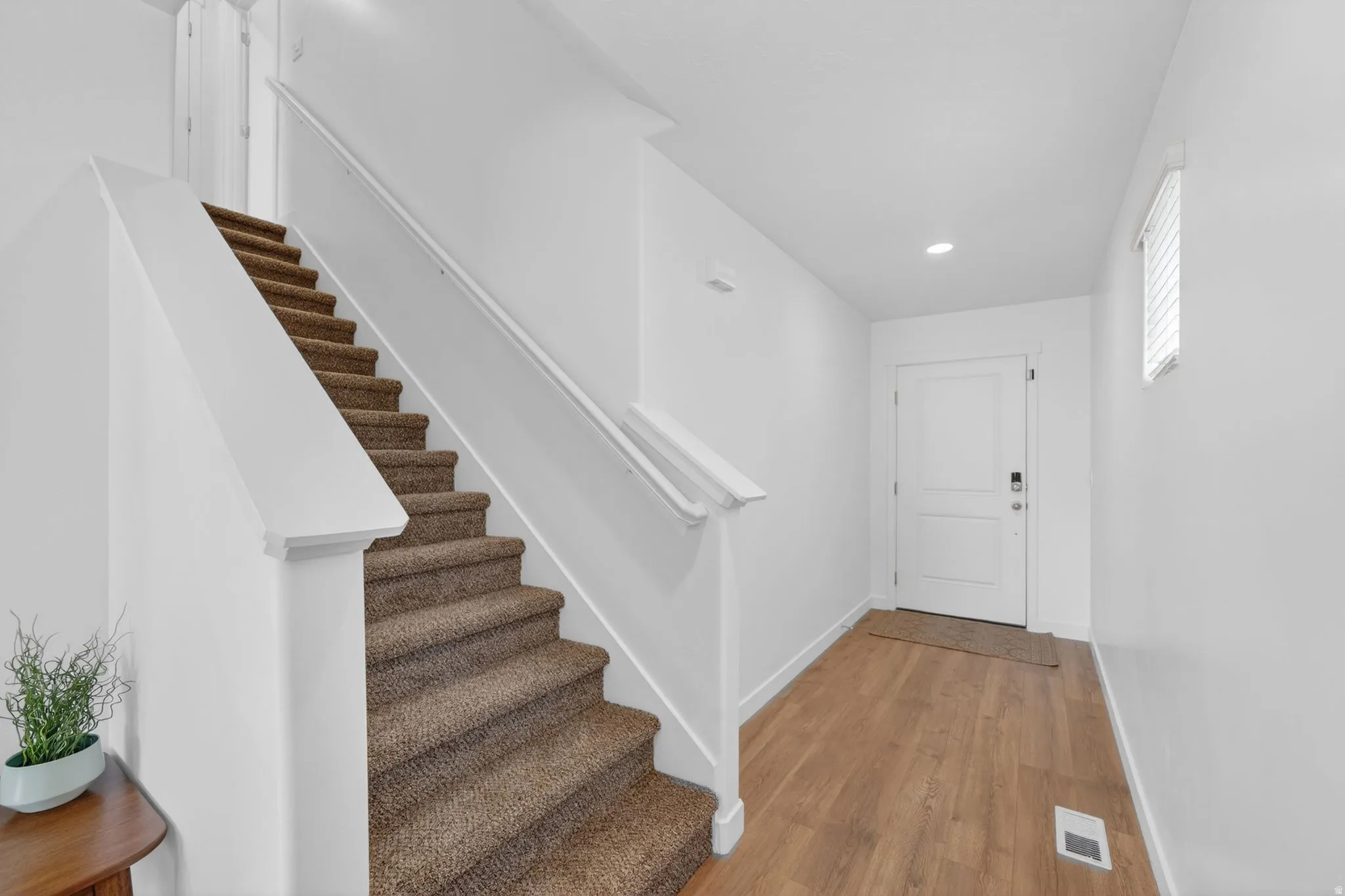 Front entry featuring wood-finish flooring, a contemporary white door, and recessed lighting