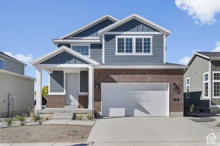 Two-story exterior featuring a mix of brick masonry and horizontal siding, covered front porch, and an attached two-car garage