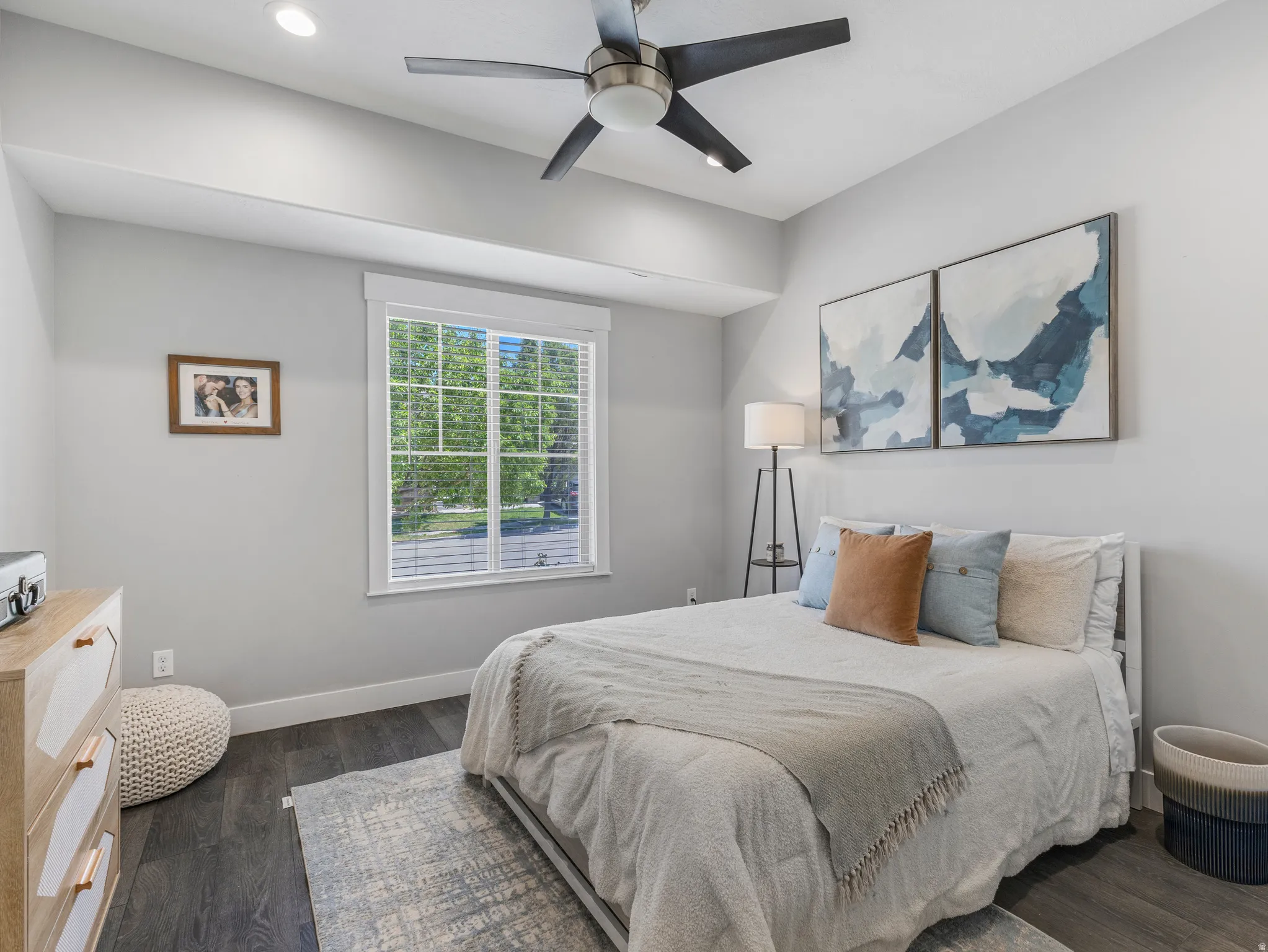 Spacious room featuring dark wood-finish flooring, a contemporary ceiling fan, recessed lighting, and a large window with blinds