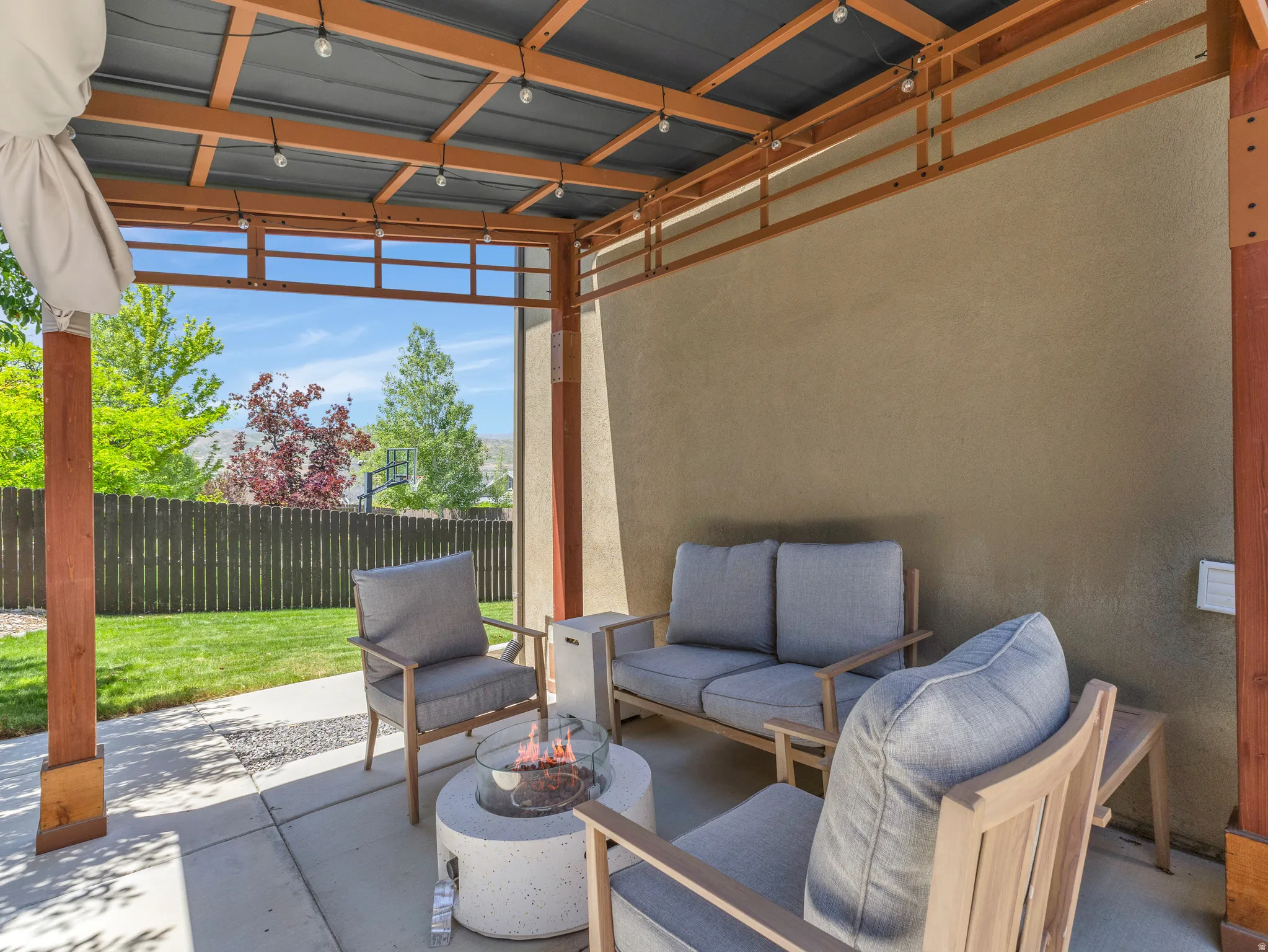 Covered patio featuring a solid roof, string lighting, and a stucco exterior wall
