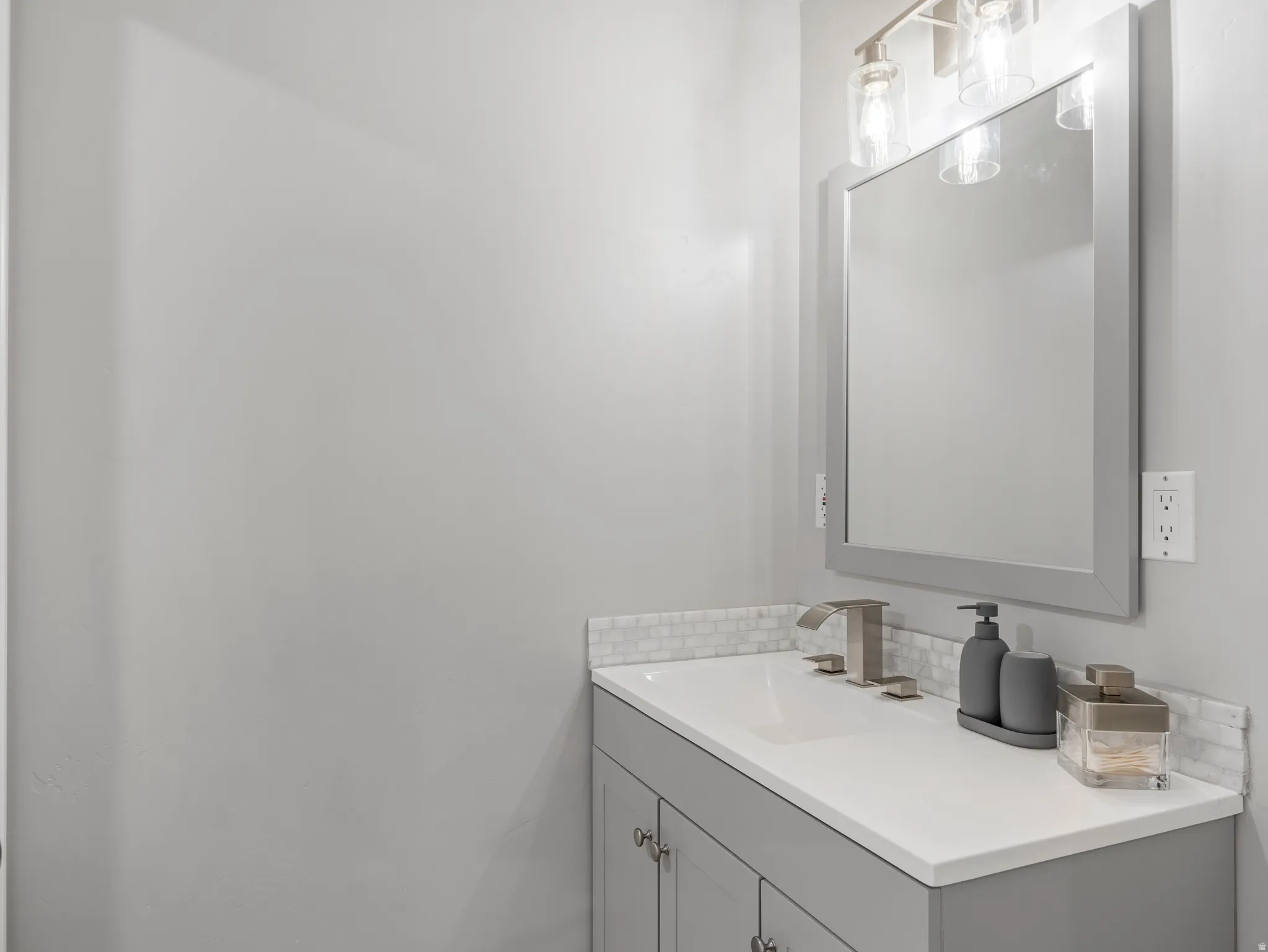 Vanity featuring a white countertop with an integrated sink, a brushed nickel faucet, and a subway tile backsplash