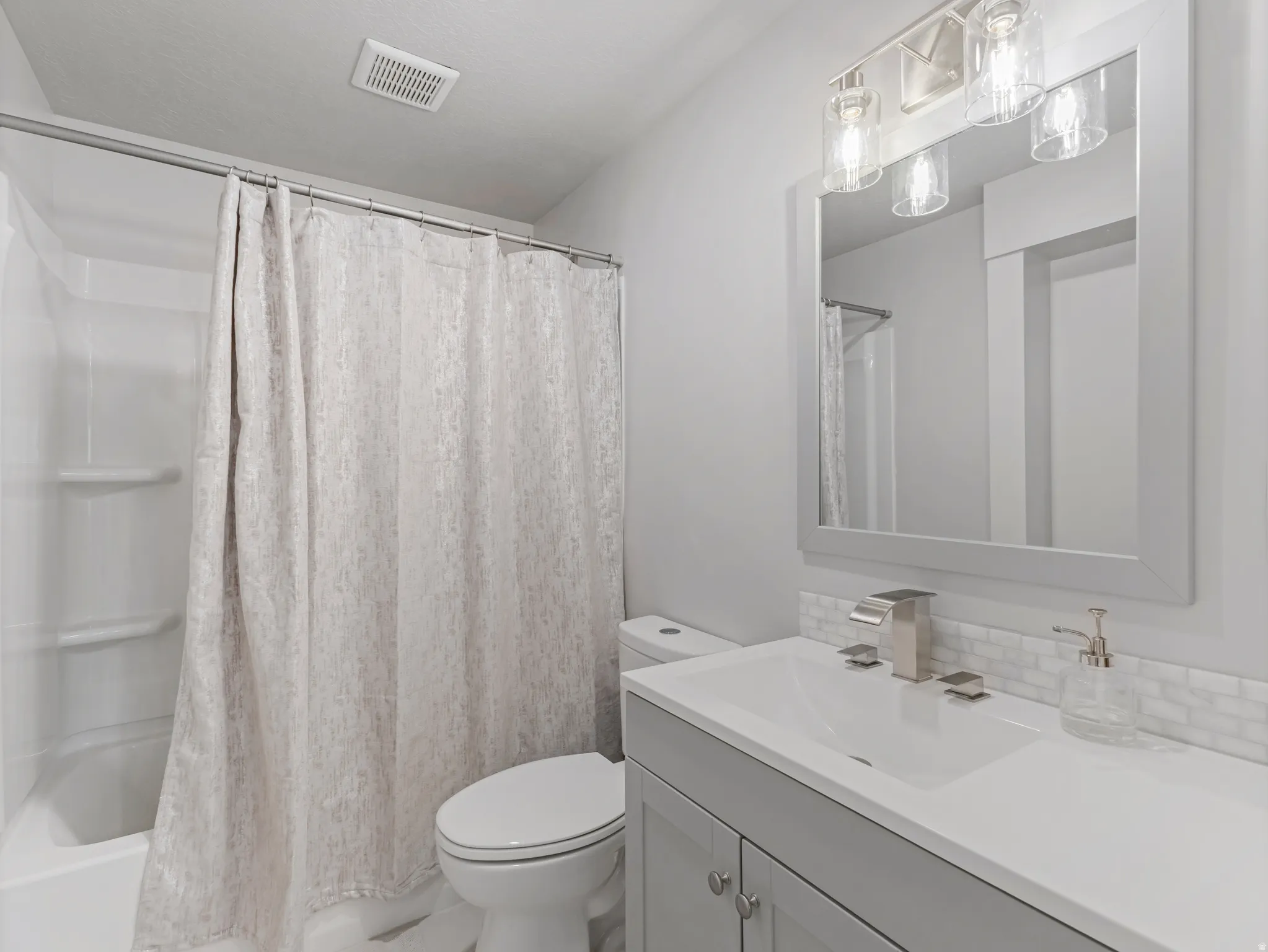 Bathroom featuring a white bathtub, toilet, and vanity with a rectangular sink